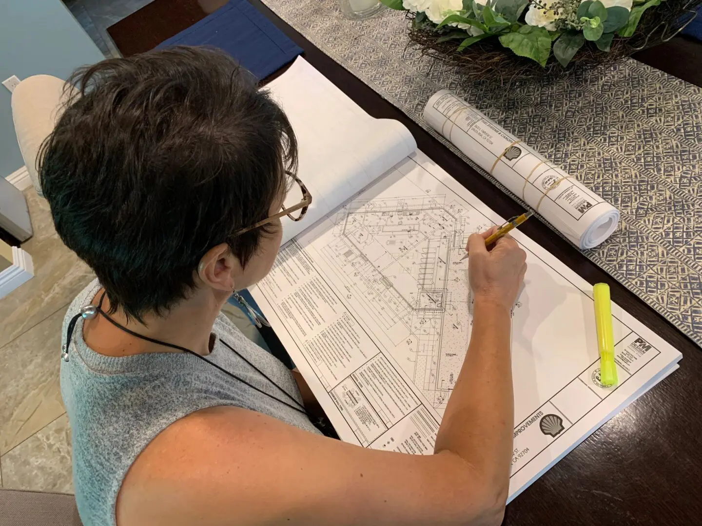 Person reviewing architectural blueprints at table